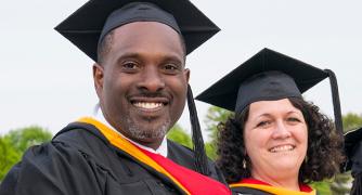 Two recently graduated people smiling at the camera
